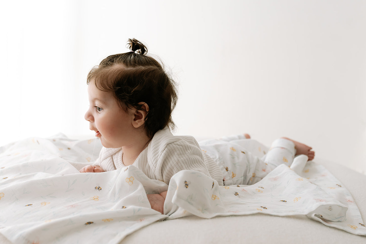 Baby lying on a white muslin with Nestle and Blooms' exclusive print displaying their versatile use