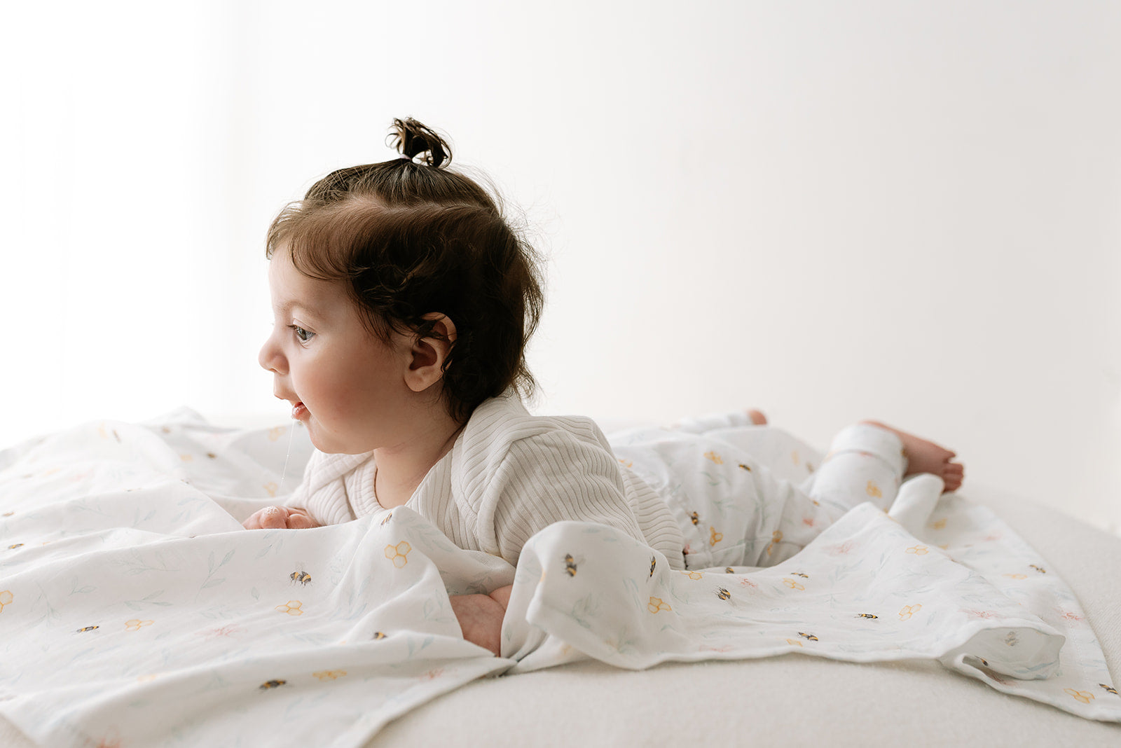 Baby lying on a white muslin with Nestle and Blooms' exclusive print displaying their versatile use