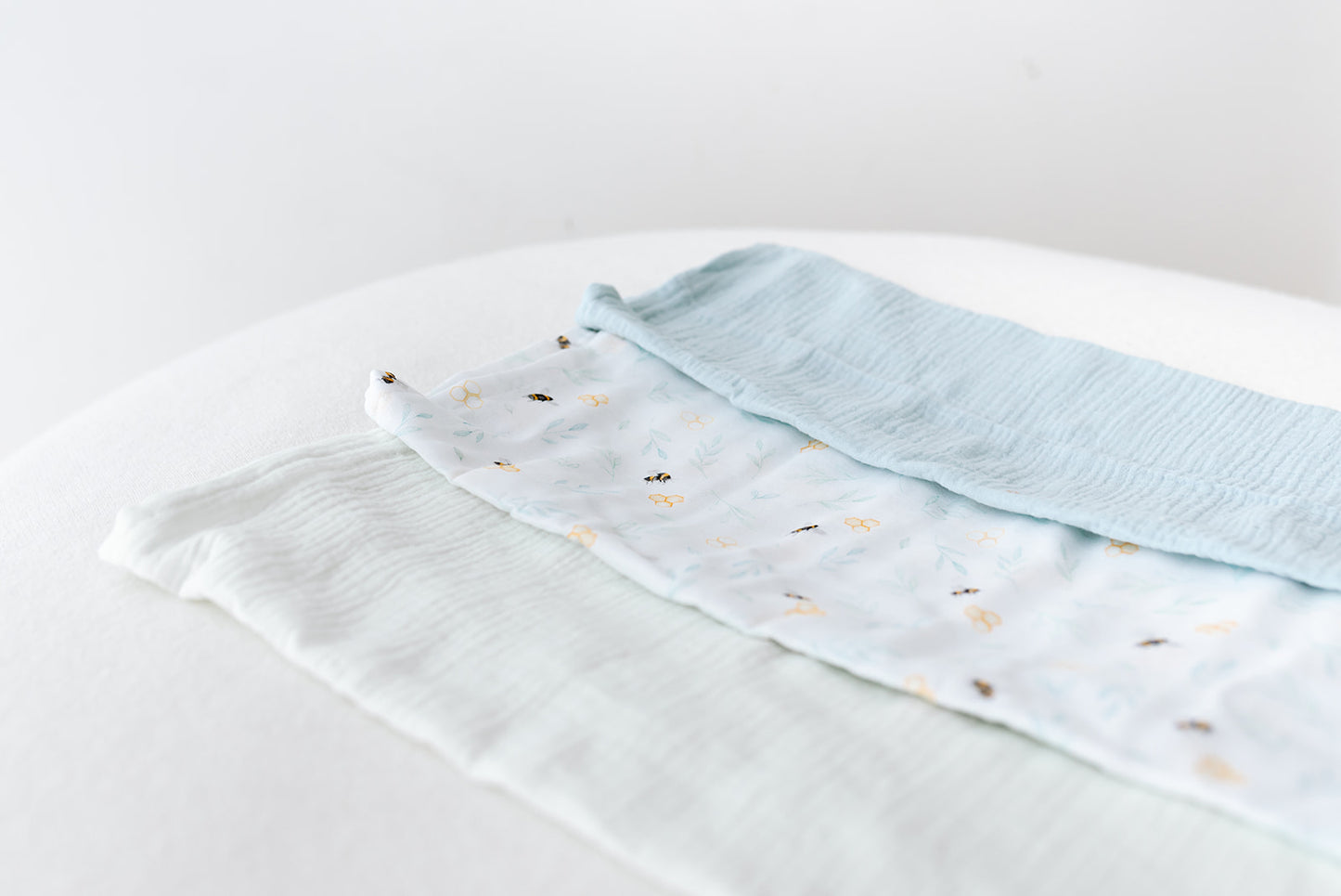 A trio of organic muslin cloths in mint, light blue and our exclusive gender neutral bee print 