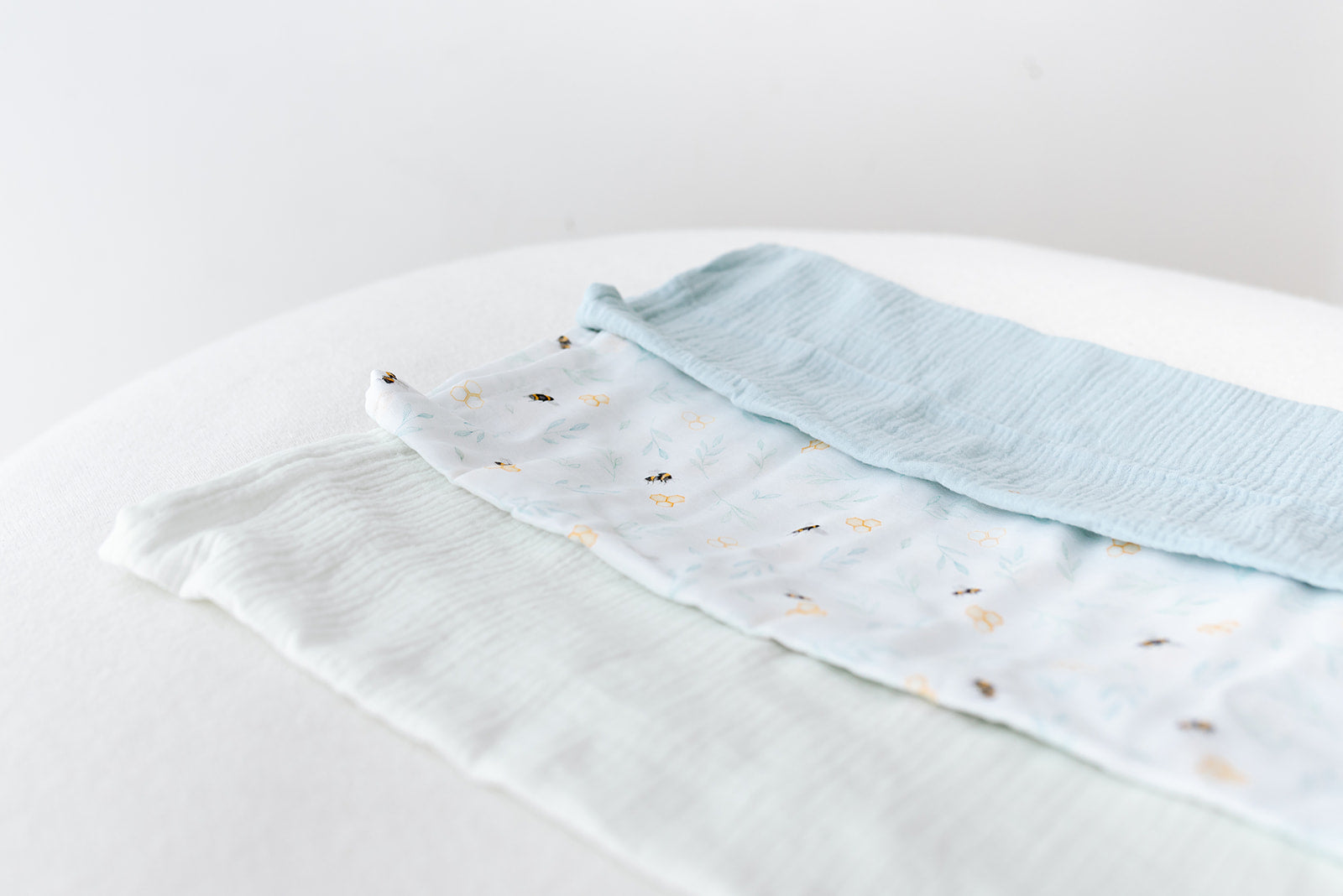 A trio of organic muslin cloths in mint, light blue and our exclusive gender neutral bee print 